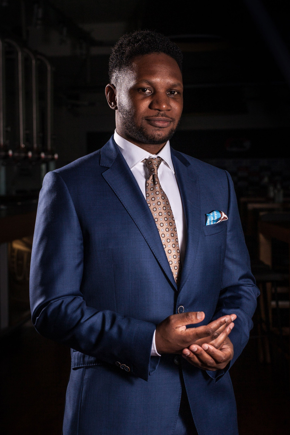 een man in een pak en stropdas die in een donkere kamer staat