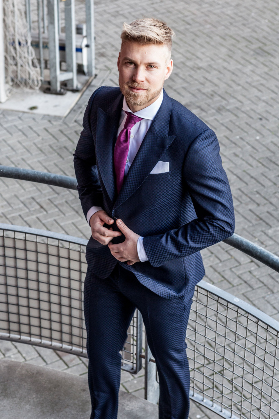 een man in een pak en stropdas staande op een balustrade