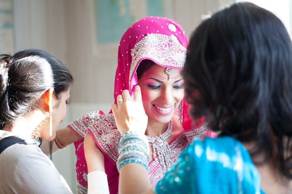 een vrouw in een roze sari maakt zich klaar om haar sieraden om te doen