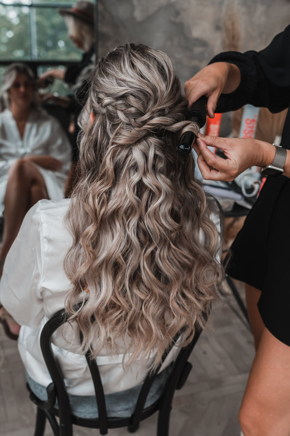 een vrouw met lang, krullend haar die haar haar laat doen