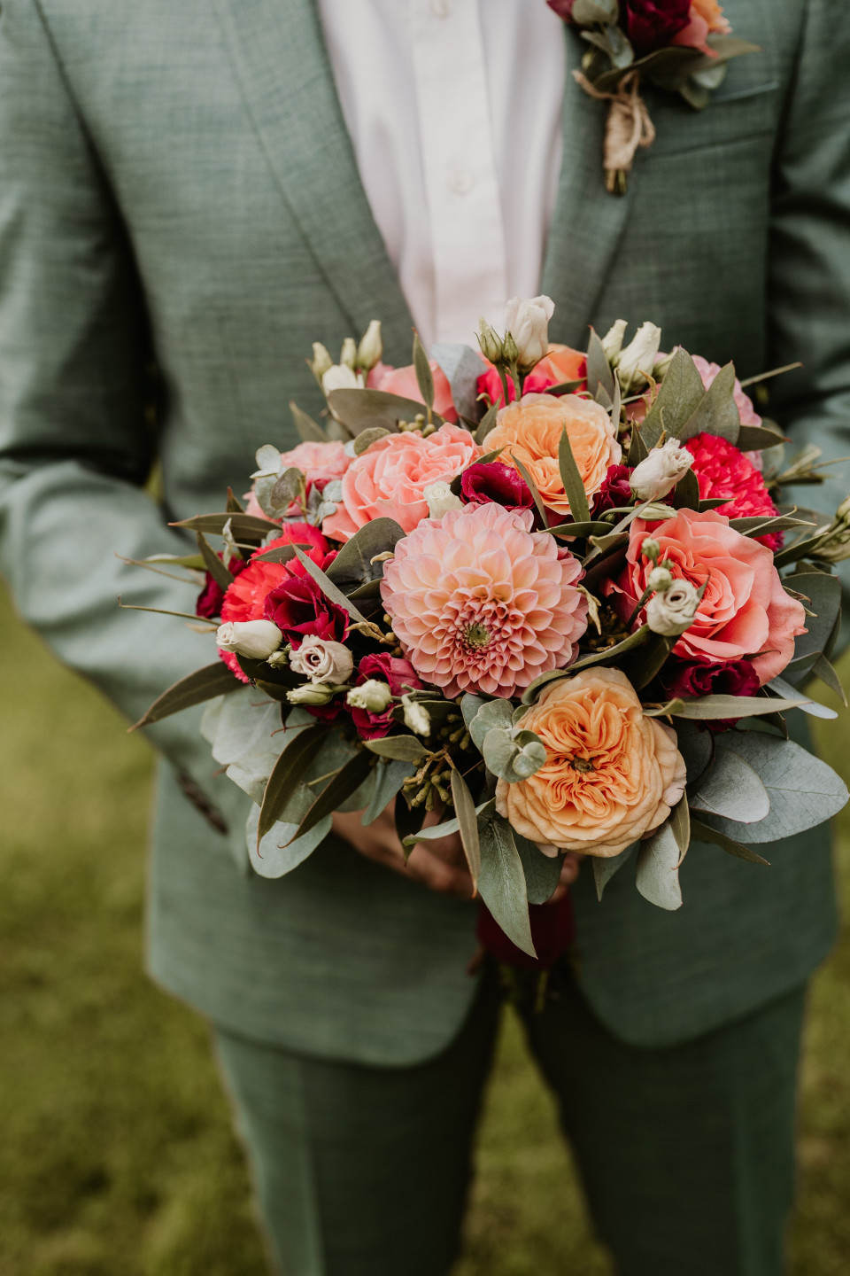 een man in een groen pak met een boeket