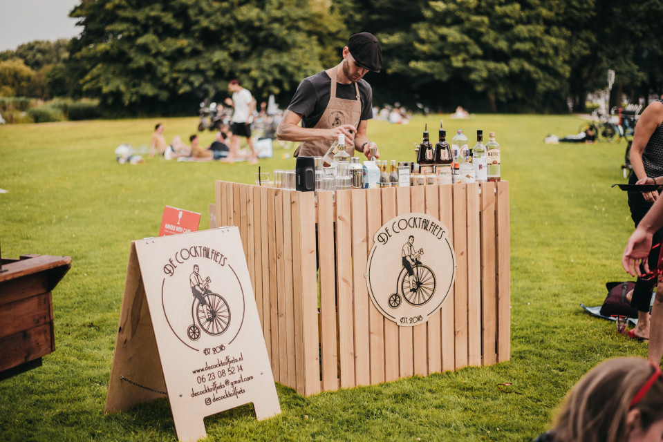 een man die achter een houten bar staat in een park