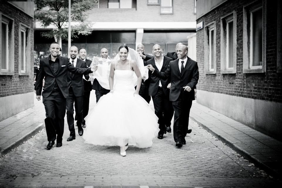 een zwart-wit foto van een bruid en bruidegom die over een straat lopen