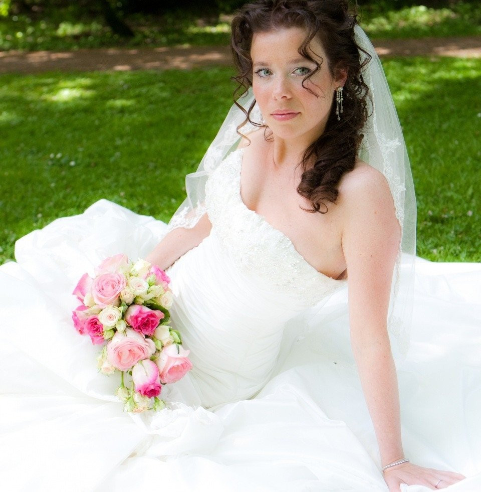 een vrouw in een trouwjurk zit op het gras