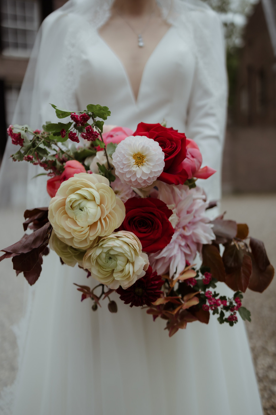 een bruid die een boeket rode en witte bloemen vasthoudt