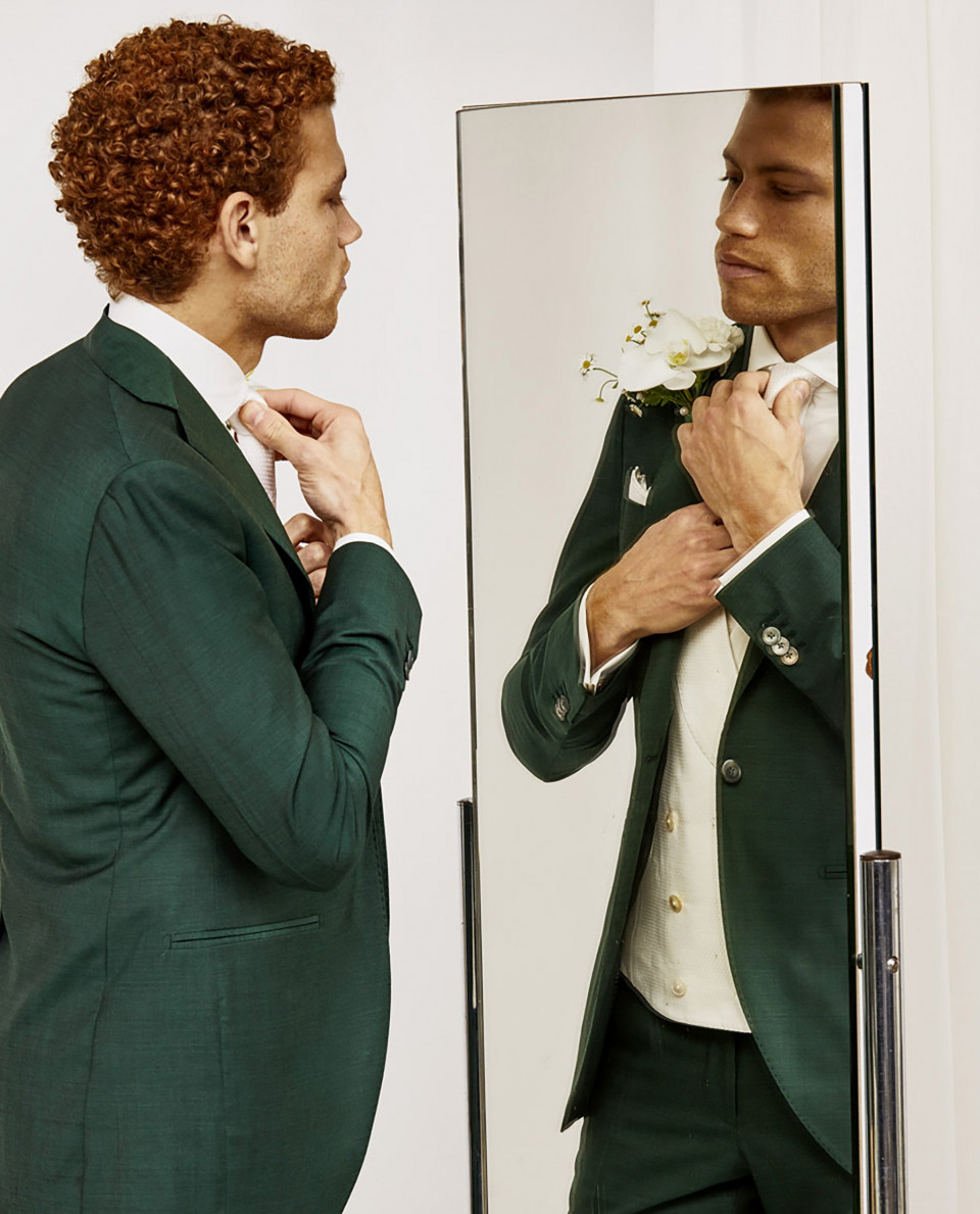 een man in een groen pak kijkt naar zichzelf in de spiegel