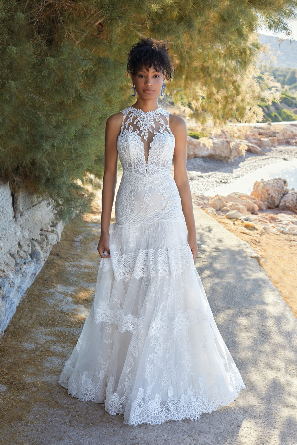 Deze betoverende trouwjurk heeft een Fit & Flare silhouet dat elegant het lichaam omhult voordat het uitloopt in een zachte, vloeiende rok, waardoor het een ideale keuze is voor een zandloper lichaamstype. De ingewikkelde kanten details en elegante structuur maken het perfect voor een verscheidenheid aan locaties, van een romantische ceremonie aan het strand tot een traditionele kerkelijke bruiloft.