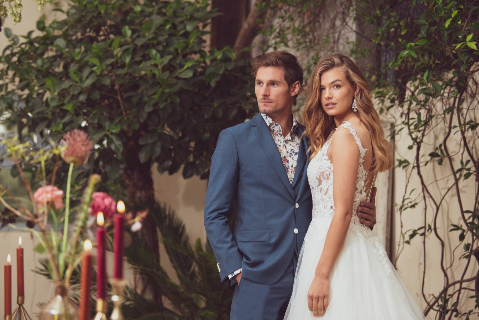 een man en vrouw in trouwkledij staan naast een boom