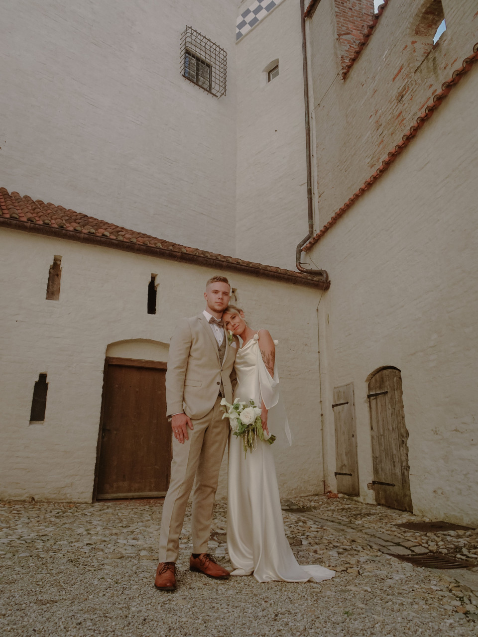 een bruid en bruidegom die voor een gebouw staan