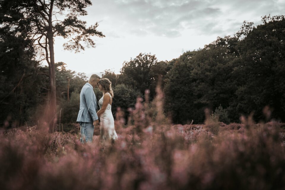 een bruid en bruidegom die door een veld met bloemen lopen