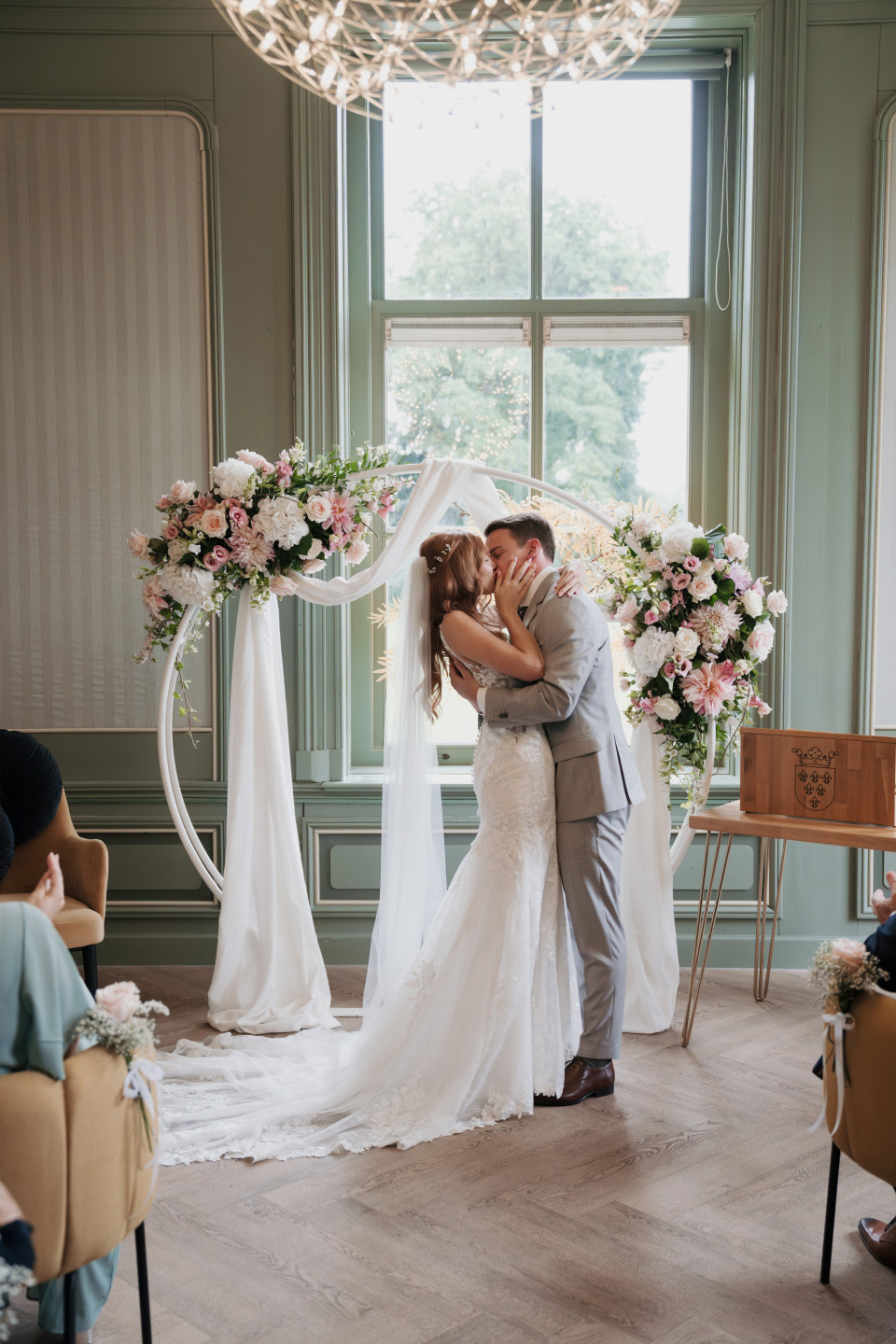 een bruid en bruidegom die voor een raam kussen