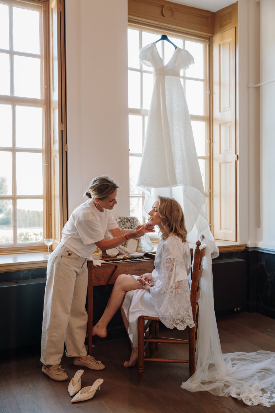 een vrouw die een andere vrouw helpt haar trouwjurk aan te trekken