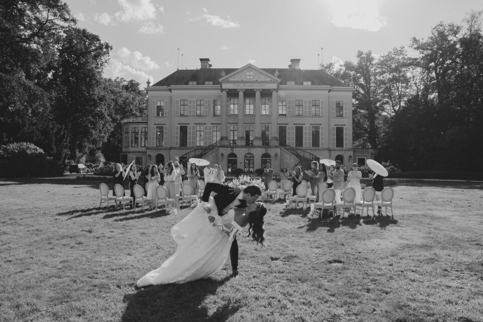 een zwart-witfoto van een bruid en bruidegom voor een groot herenhuis