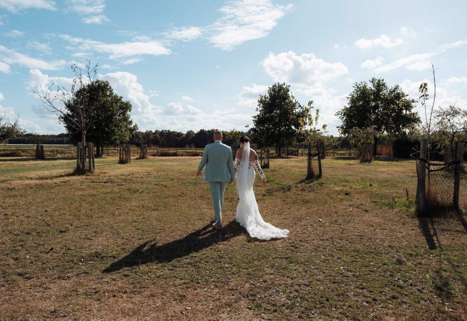 een bruid en bruidegom die samen in een veld lopen