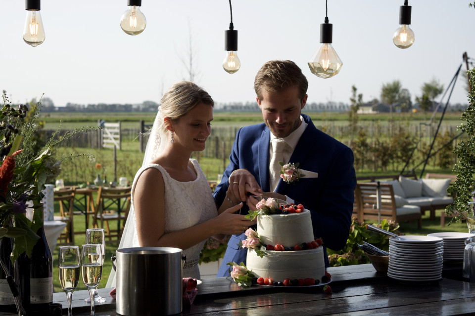 een bruid en bruidegom die samen een taart aansnijden