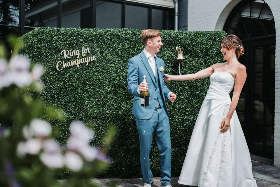 een bruid en bruidegom die een fles champagne vasthouden