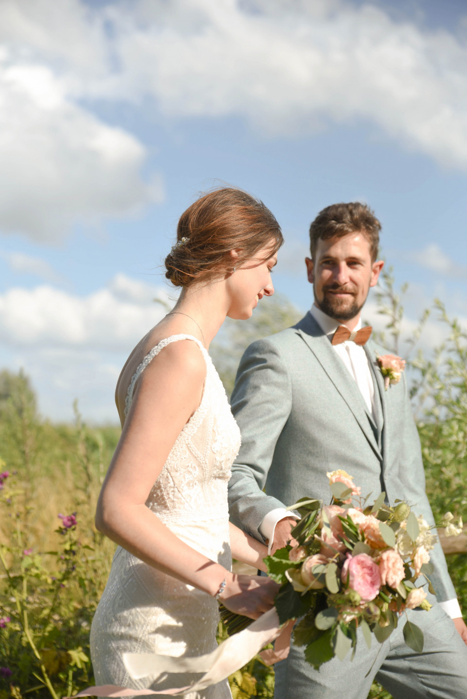 een bruid en bruidegom lopen door een veld met bloemen