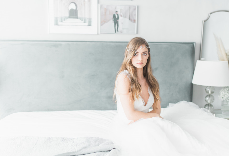 een bruid die op een bed zit in haar trouwjurk