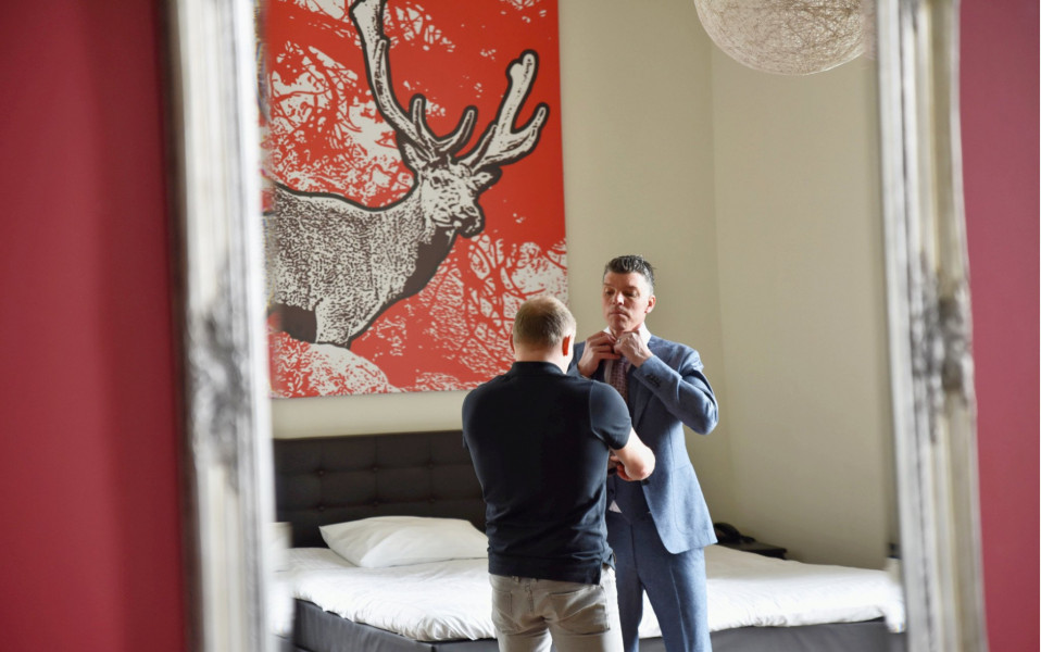 een man maakt zich klaar om zijn das voor een schilderij te doen