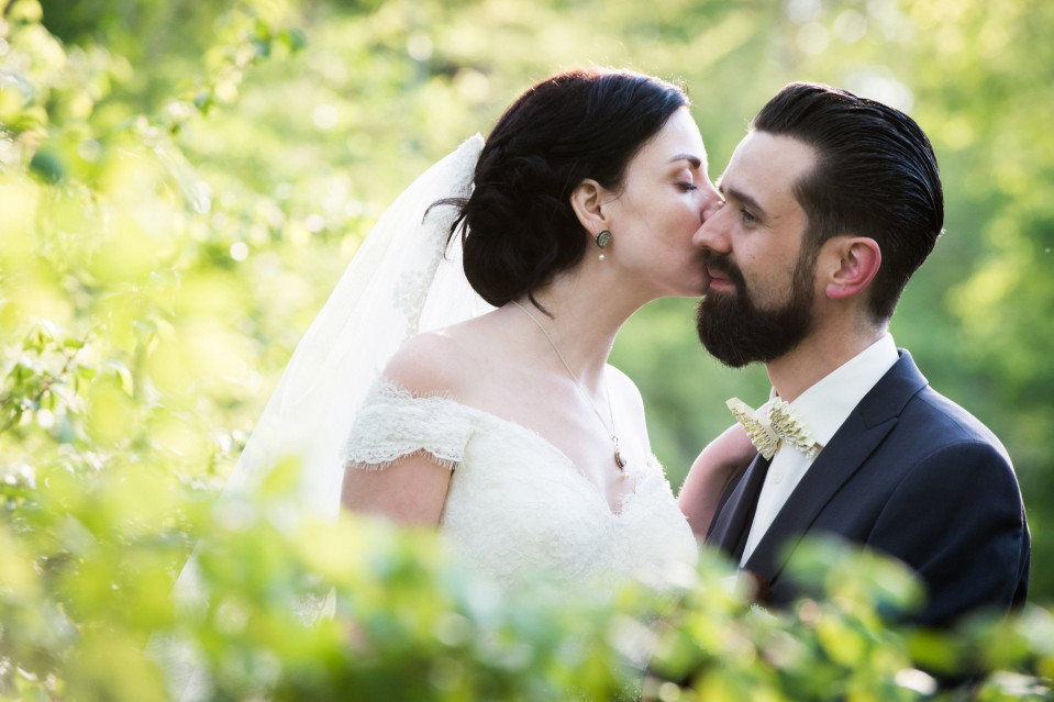 een bruid en bruidegom kussen in het bos