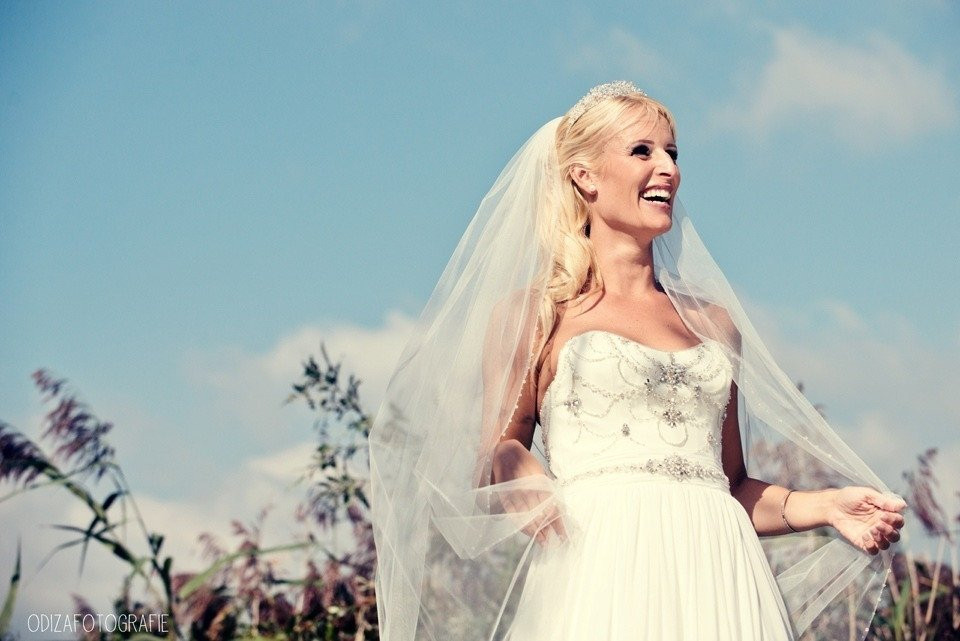 een mooie bruid glimlacht terwijl ze in een veld staat