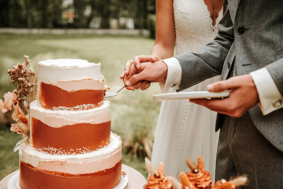 een bruidspaar snijdt samen een taart