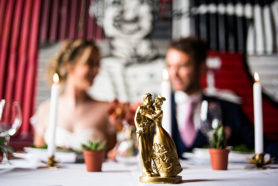 een bruid en bruidegom zitten aan tafel met een gouden standbeeld