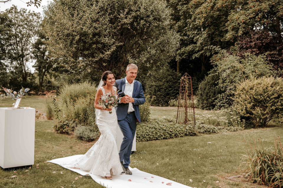 een bruid en bruidegom lopen het gangpad af in een tuin