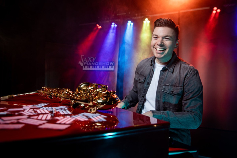 een man die aan een tafel zit met een saxofoon voor hem