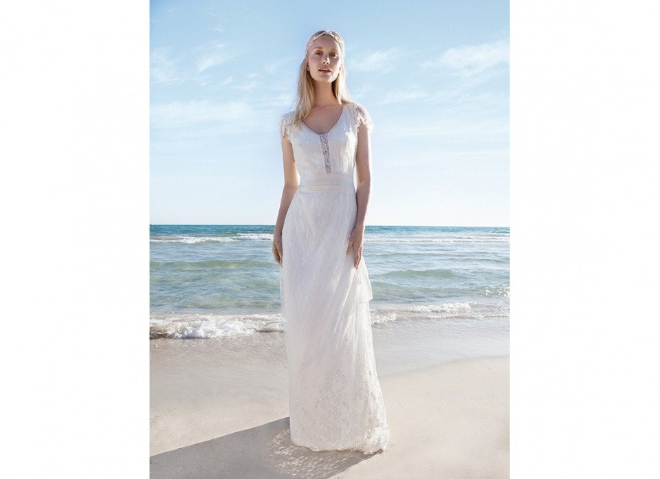 een vrouw in een trouwjurk die op het strand staat