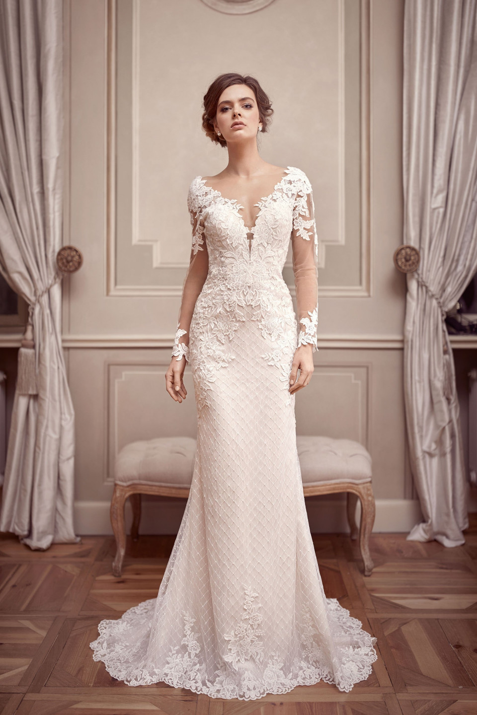 de mooie bruid in een lange kanten trouwjurk met lange mouwen