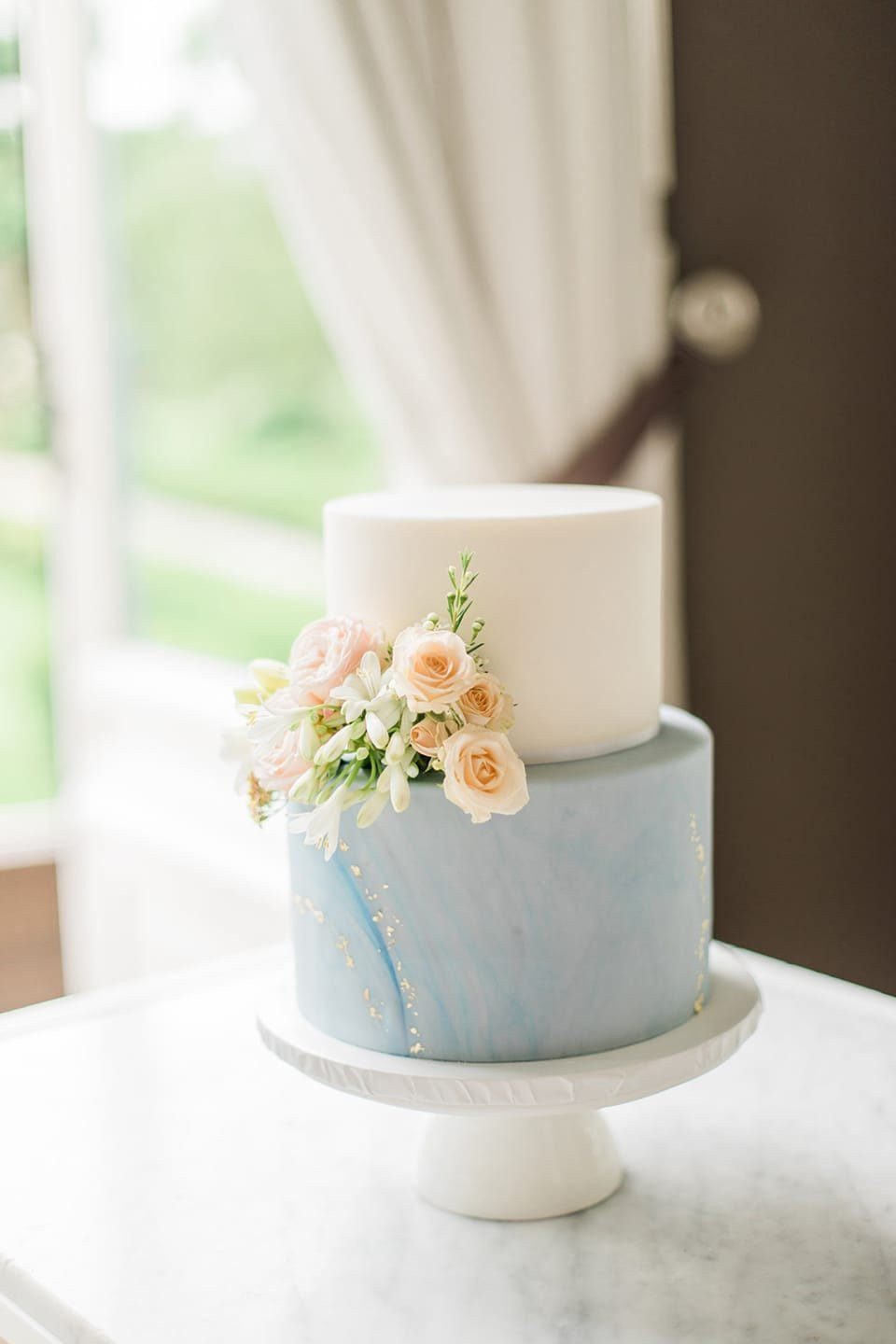 een blauwe en witte bruiloftstaart met bloemen