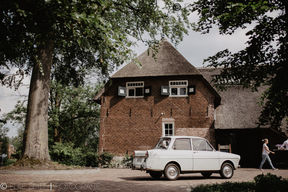 een kleine witte auto geparkeerd voor een bakstenen huis