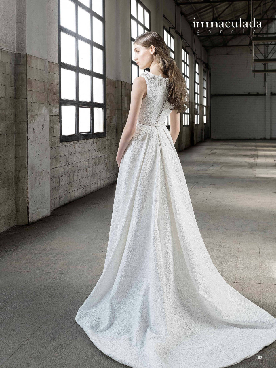 een vrouw in een witte trouwjurk die in een lege loods staat