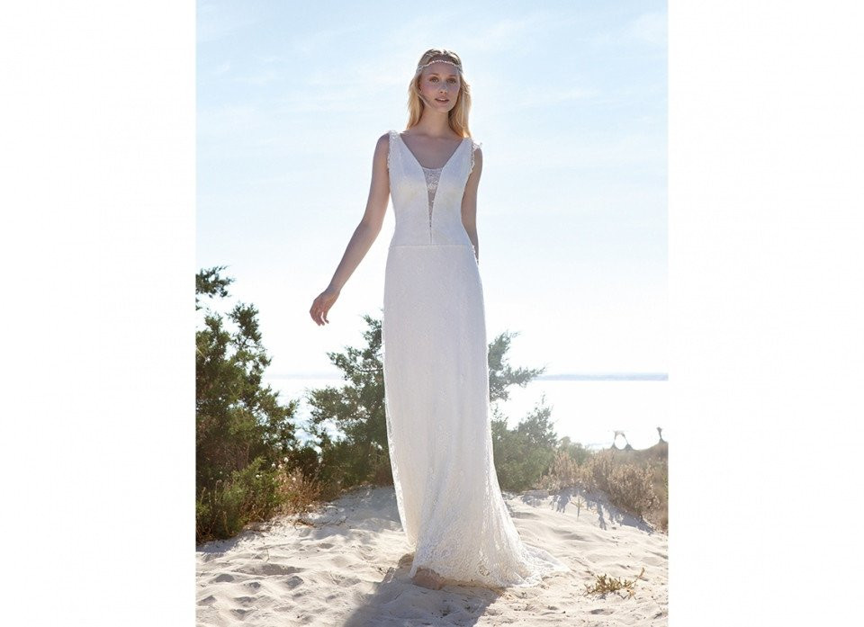 een vrouw in een witte trouwjurk die op het strand staat