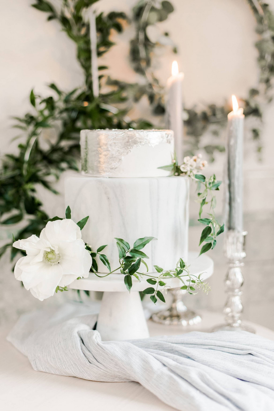 een witte trouwtaart met groen en kaarsen