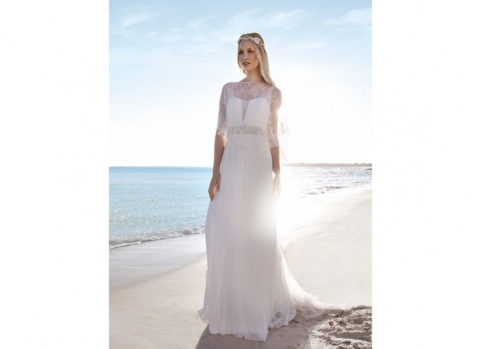 een vrouw in een trouwjurk die op het strand staat