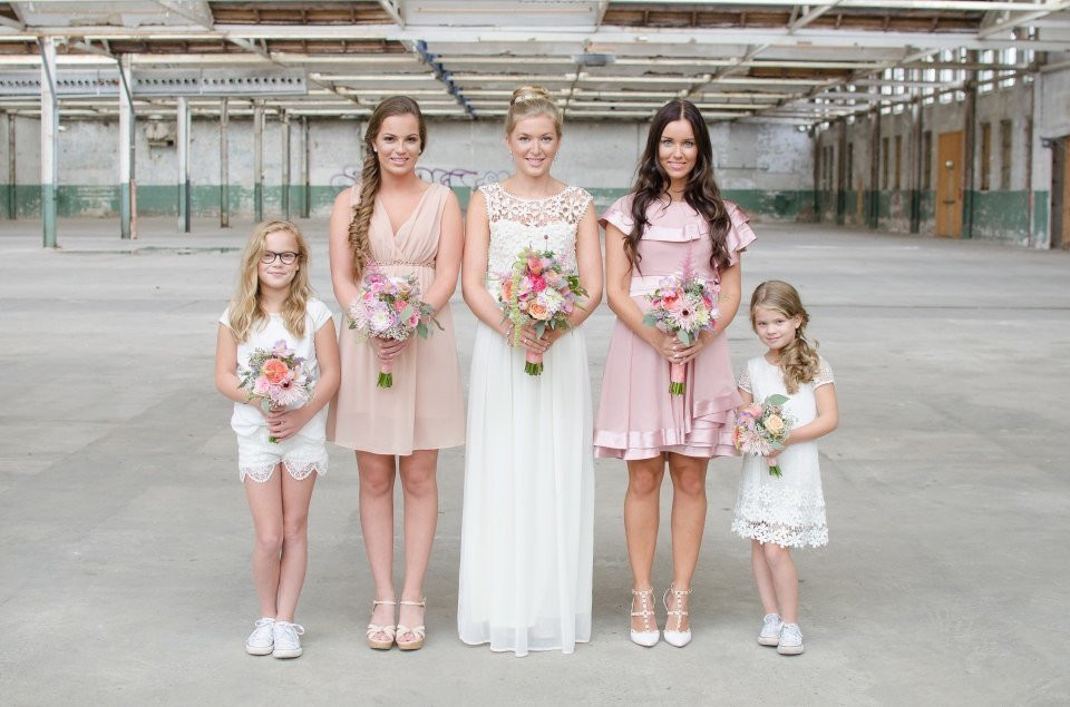 een groep bruidsmeisjes en bloemenmeisjes in roze jurken