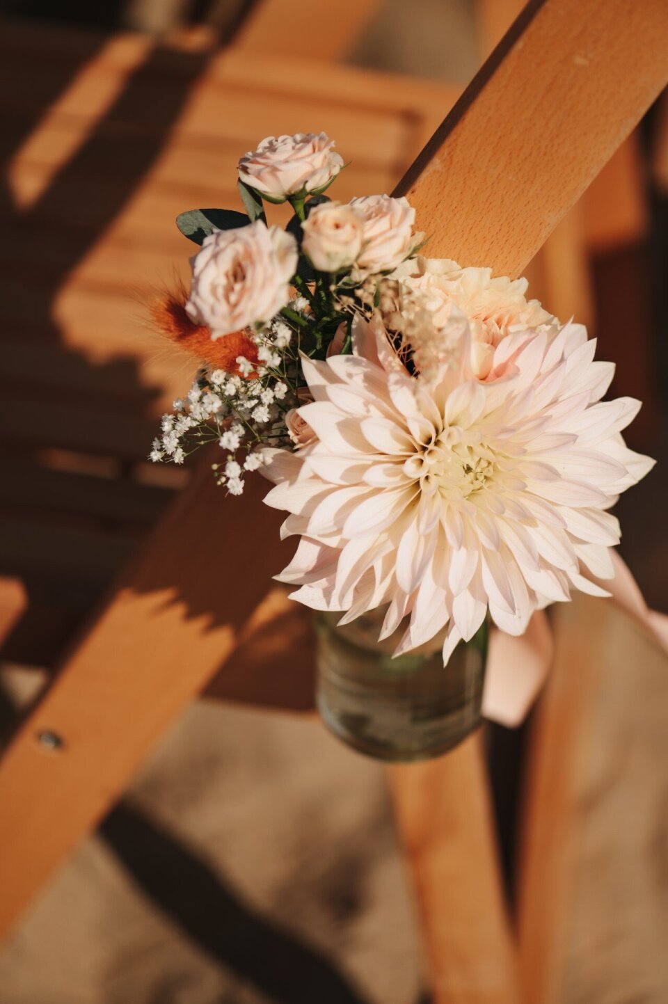 een vaas met bloemen op een houten stoel