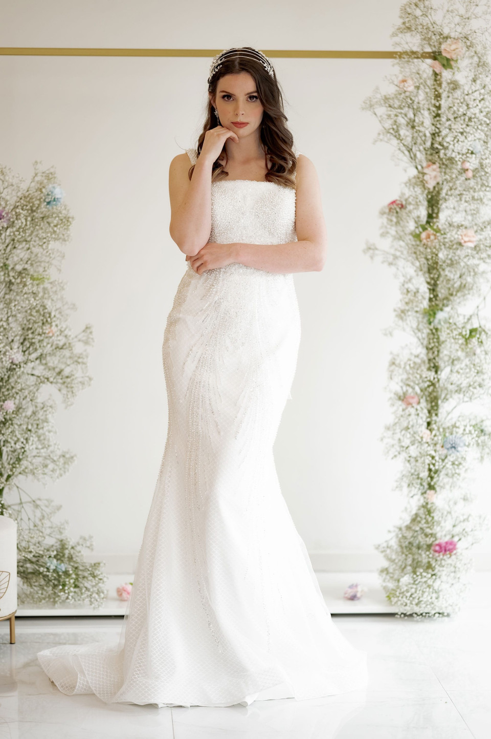 Deze elegante trouwjurk heeft een zeemeermin silhouet dat elegant het lichaam volgt voordat het uitloopt bij de knie, waardoor een prachtige zandloper vorm ontstaat. De jurk is versierd met ingewikkeld kralenwerk en pailletten, die een luxueuze glans toevoegen die perfect is voor een formele of glamoureuze locatie. Het ontwerp is bijzonder geschikt voor een zandloper lichaamstype, omdat het de rondingen accentueert en zorgt voor een evenwichtige verhouding.
