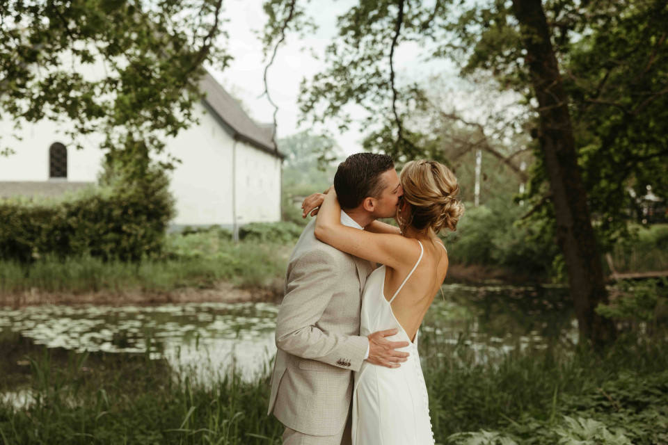 een bruid en bruidegom die kussen voor een vijver
