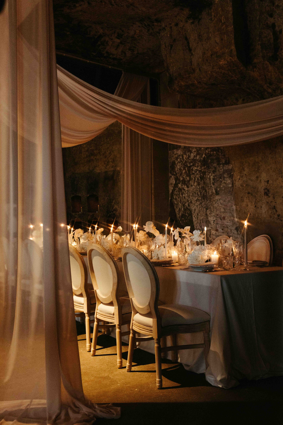 een lange tafel met kaarsen erop in een zwak verlichte kamer