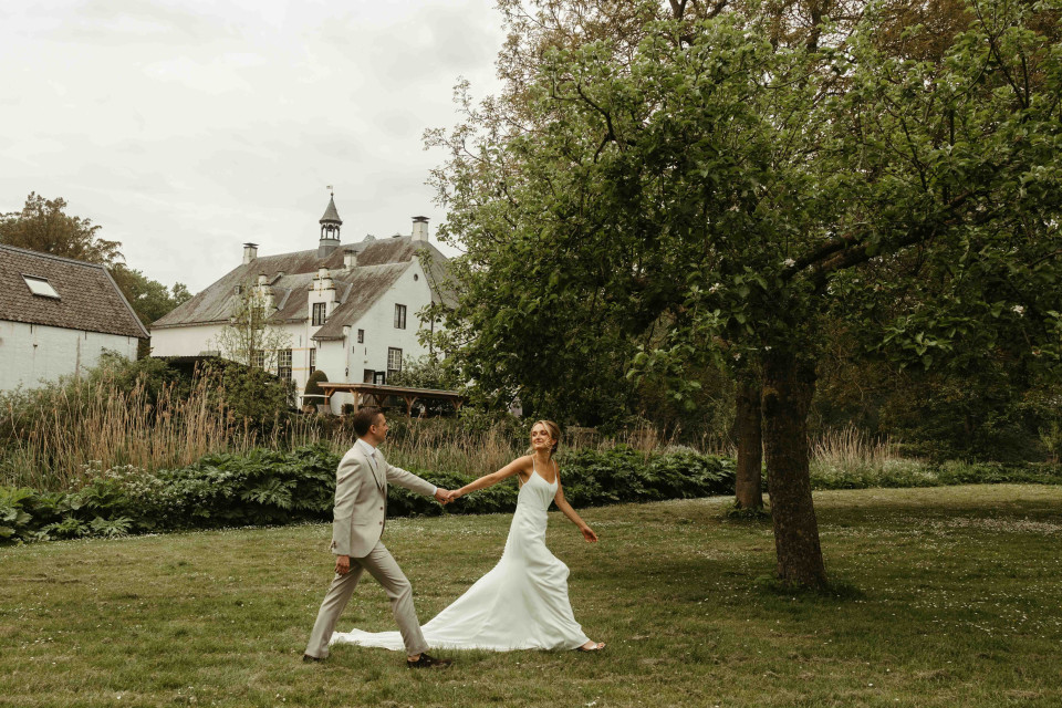 een bruid en bruidegom die door het gras lopen