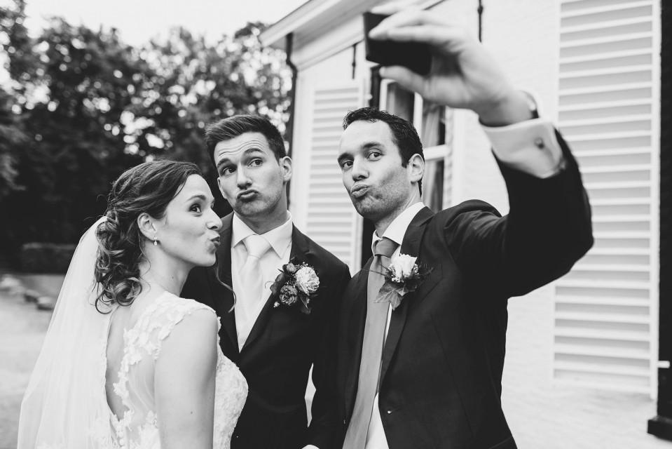 een bruid en bruidegom die een selfie nemen met hun vrienden