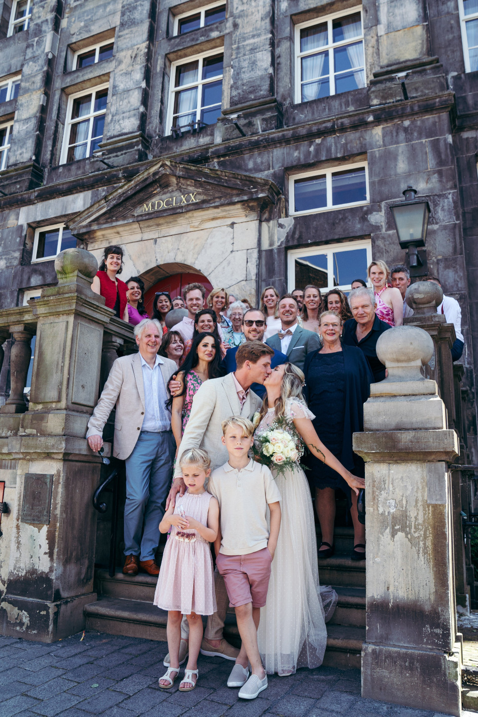 een bruiloftsgroep poseert voor een foto voor een gebouw