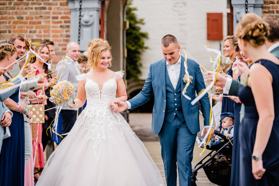 een bruid en bruidegom lopen het gangpad af met hun gasten
