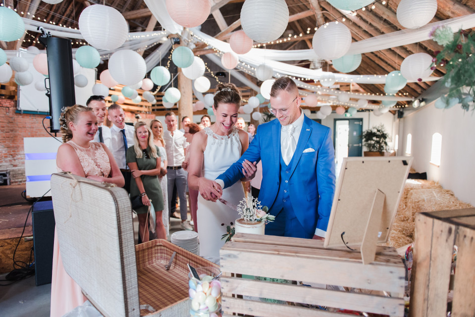 een bruidspaar dat de taart aansnijdt op hun trouwreceptie