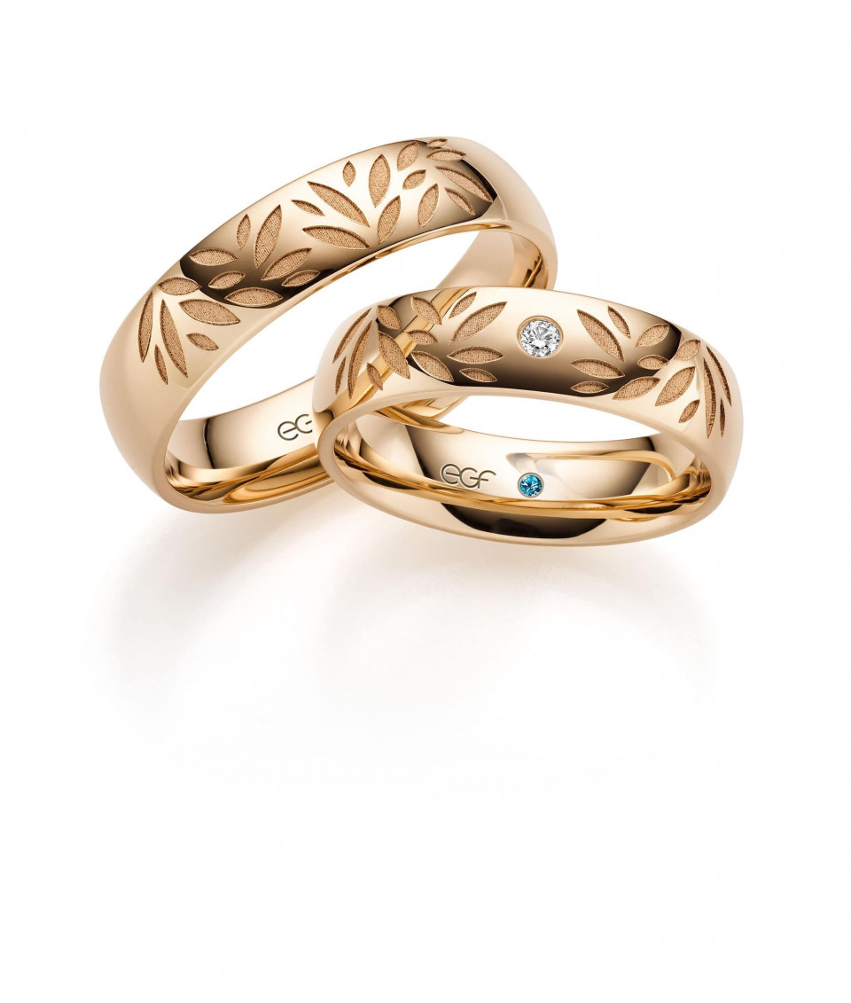 twee trouwringen met een gouden band en een blauwe diamant