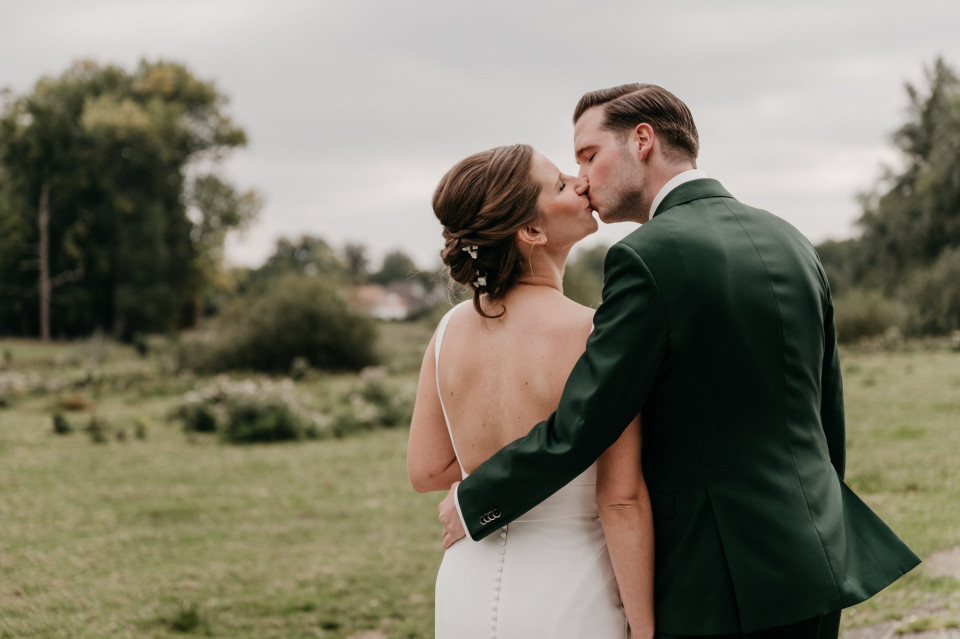 een bruid en bruidegom die in een veld kussen