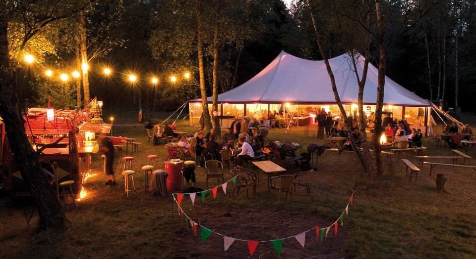 een grote tent met mensen die er 's nachts omheen zitten